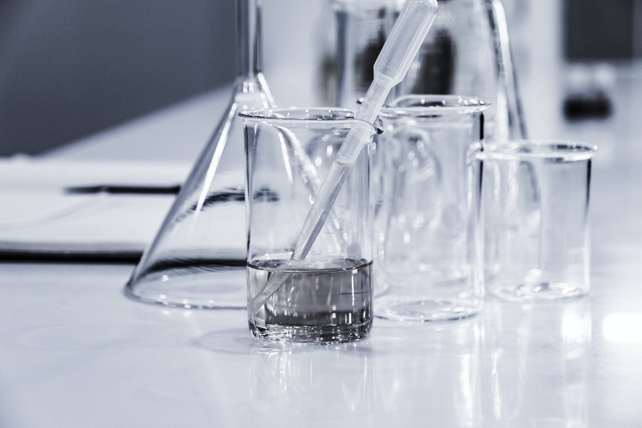 Laboratory setting with beakers and a dropper on a white surface